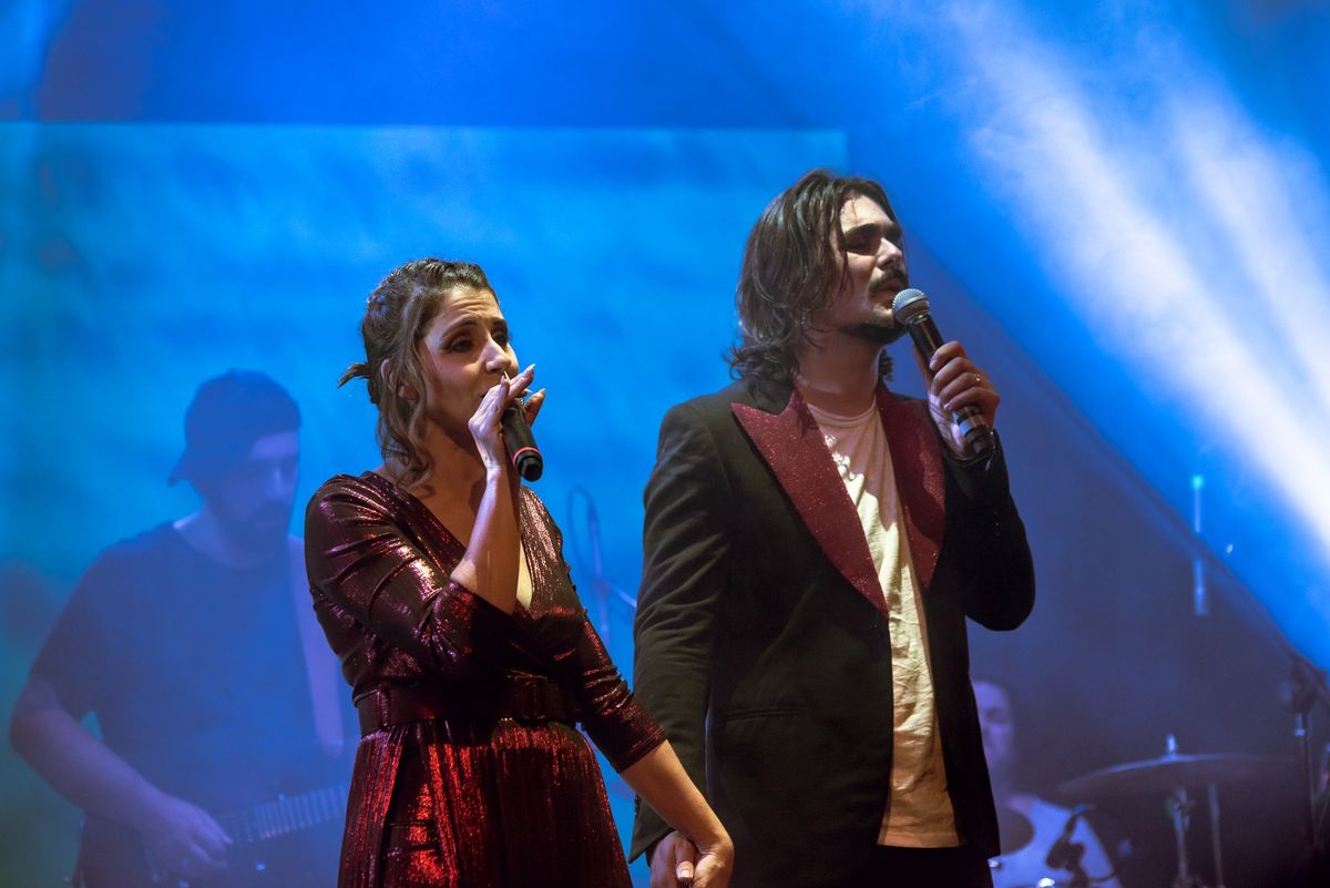 Lasimi canta in duetto sul palco di MUTOPIA, luci blu, la band alle spalle