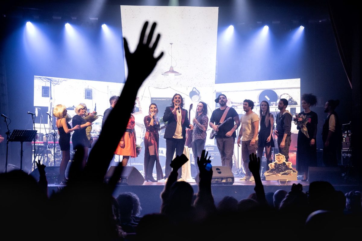 Il saluto finale di MUTOPIA: tutto il cast sul palco, le mani del pubblico alzate